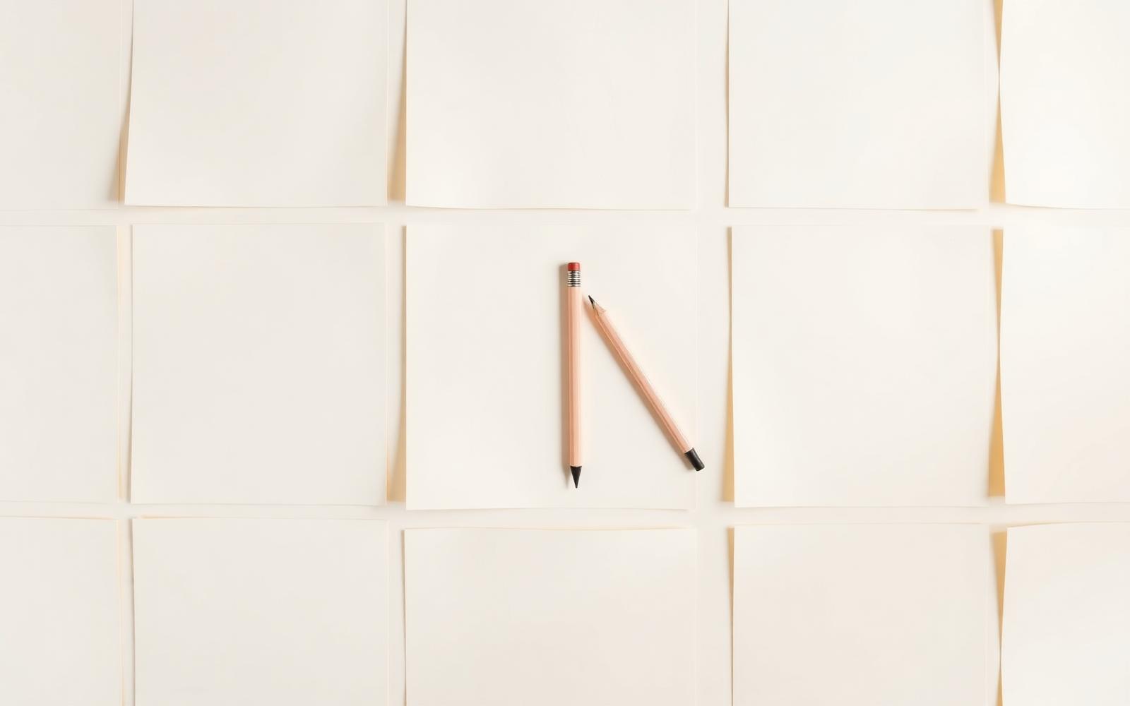 Folhas de papel em branco dispostas em grade com um lápis ao centro